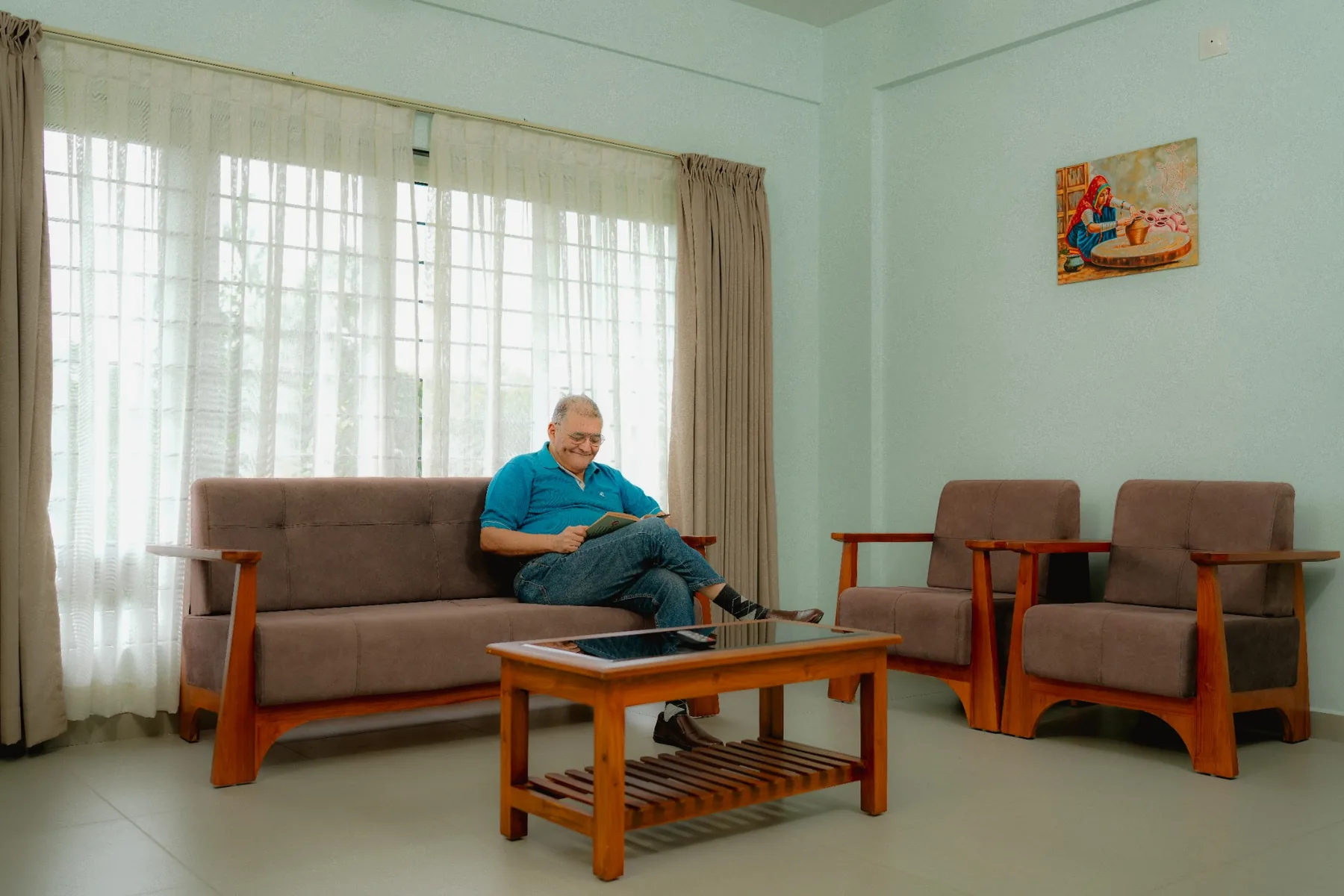 A senior resident reading comfortably in a bright lounge